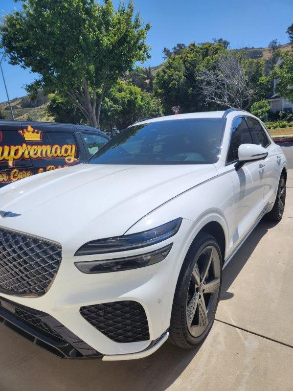 Front view of a white Genesis SUV after a full exterior detail